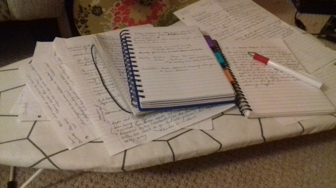 The image shows two notebooks and sheets of paper covered in writing.