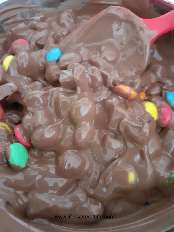 The image shows molten milk chocolate mixed with sweets.