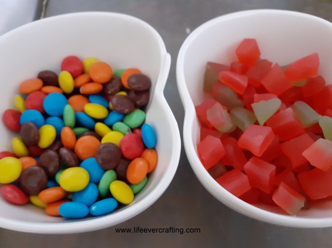 The image shows two bowls: the one on the left contains Smarties and the one on the right contains chopped Haribo Strawbs.
