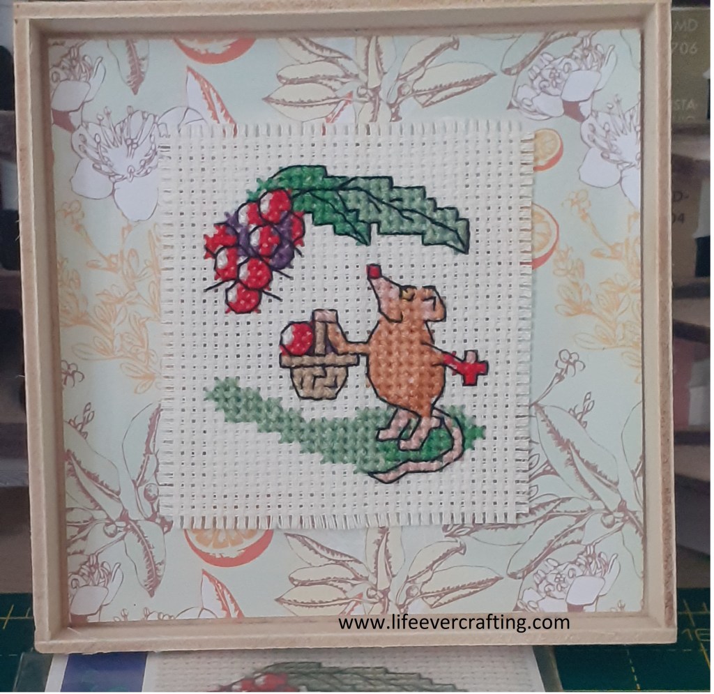 Image shows a cross-stitch of a mouse blackberrying.