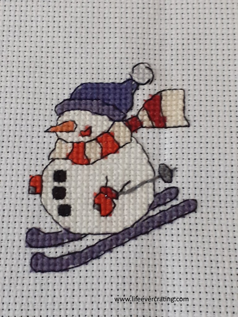 Image shows a snowman skiing. 