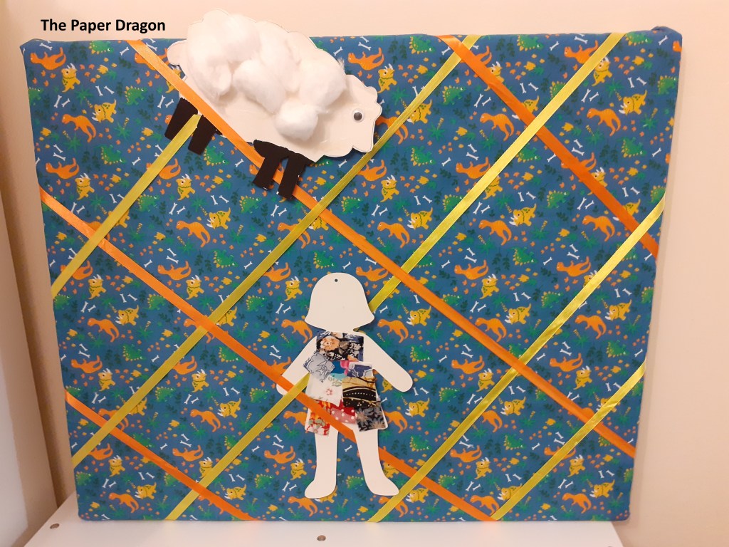 Image shows a notice board with a dinosaur pattern and yellow and orange ribbons criss-crossing it. 